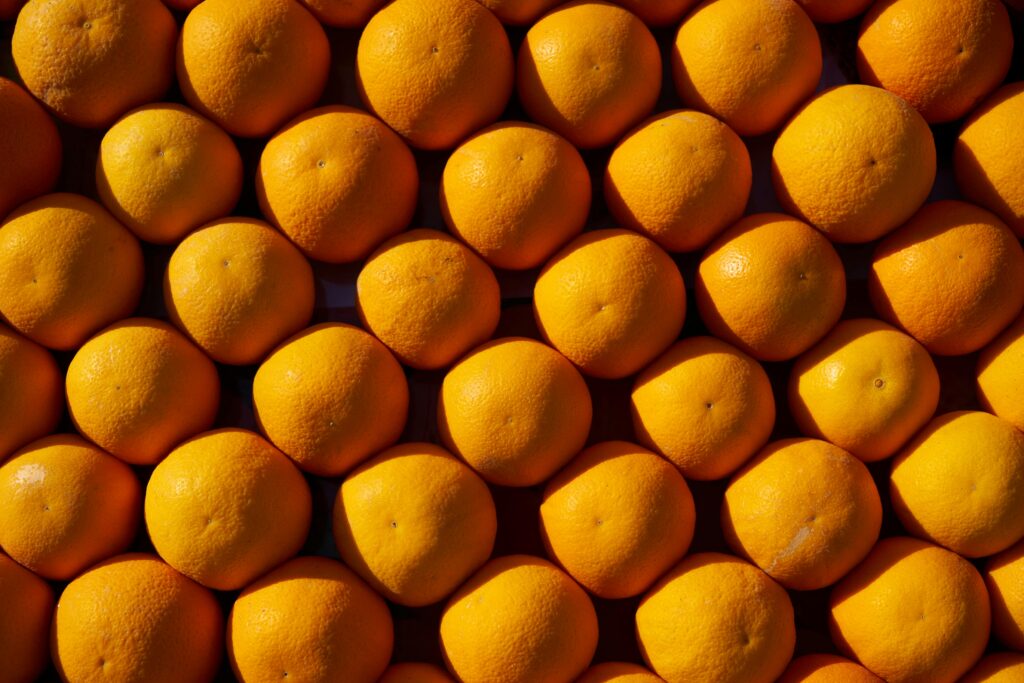 Home Top view of a neatly arranged pile of fresh oranges, showcasing vibrant color and texture.